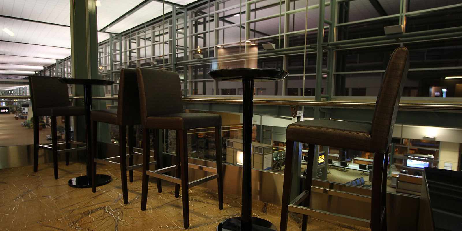 High-top tables overlook the terminal in the non-US departures Plaza Premium Lounge in Edmonton